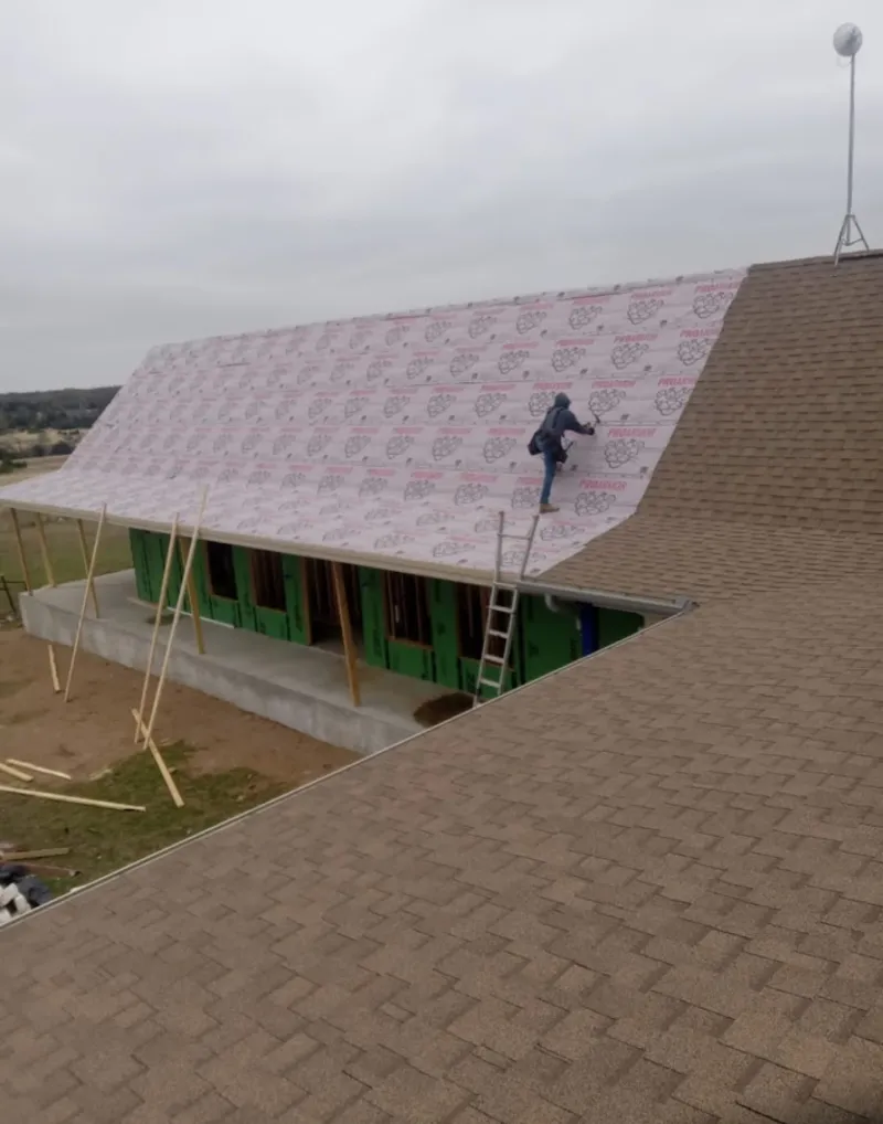 Worker preparing underlayment for a metal roof installation in Round Lake Beach
